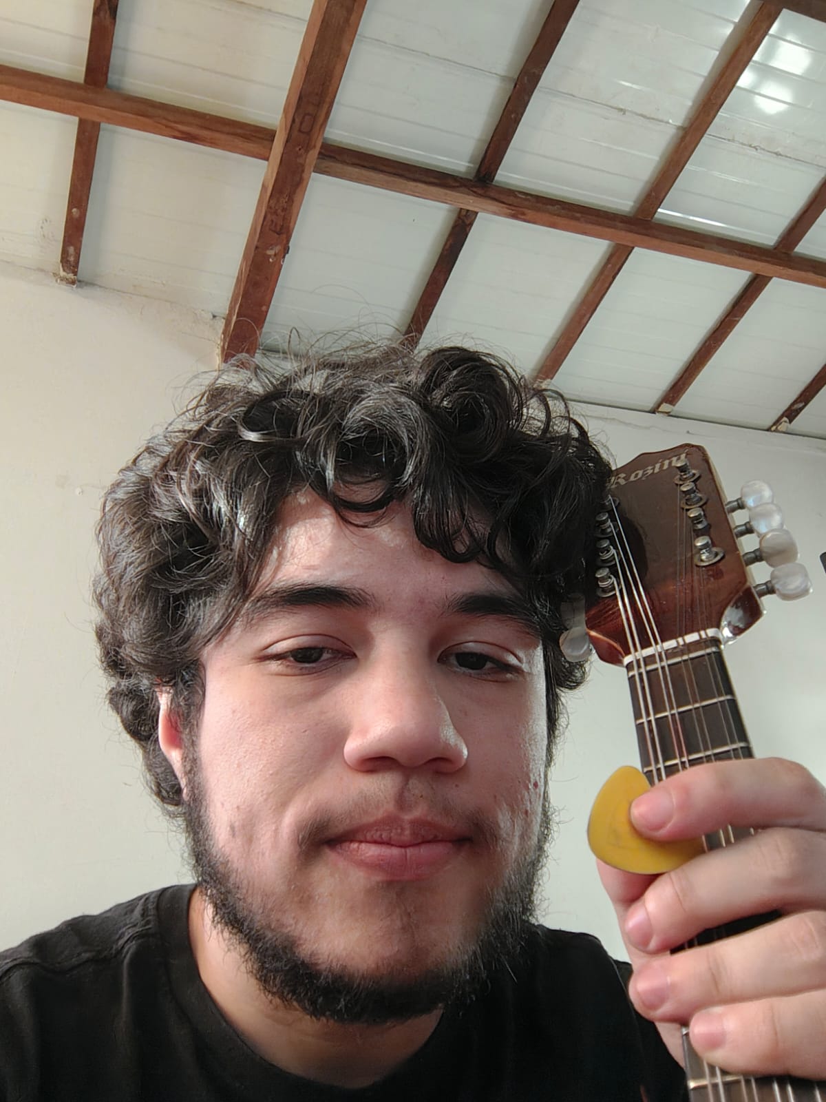 Selfie of me holding a mandolin and a yellow pick